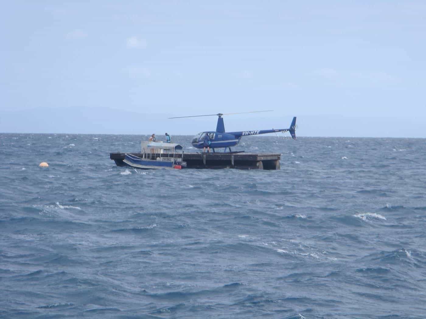 A helicopter hovering over a reef pontoon near the Great Barrier Reef