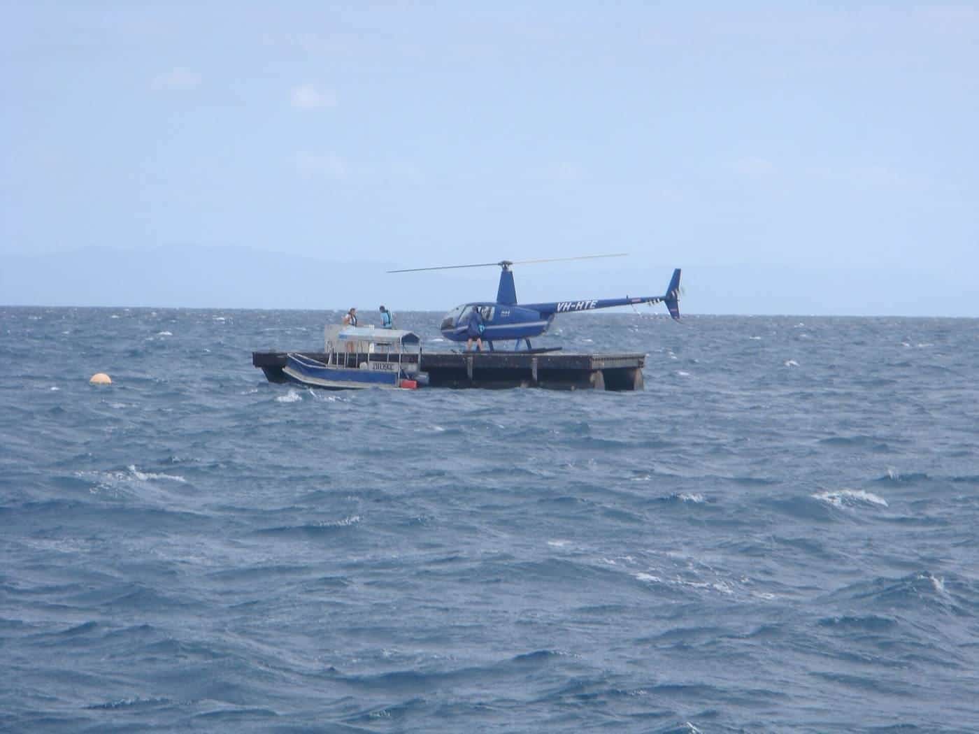 A helicopter hovering over a reef pontoon near the Great Barrier Reef